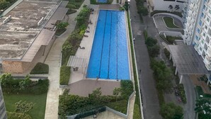 Un edificio de gran altura con piscina en la azotea, rodeado de vegetación y otros edificios.