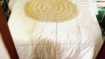 Un lit avec une couette blanche et une couverture tissée de forme circulaire.