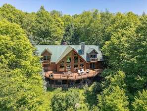 A cabin with a deck, surrounded by dense forest.