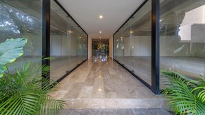 Un pasillo con paredes de vidrio y suelo de baldosas, que conduce a una puerta al final.