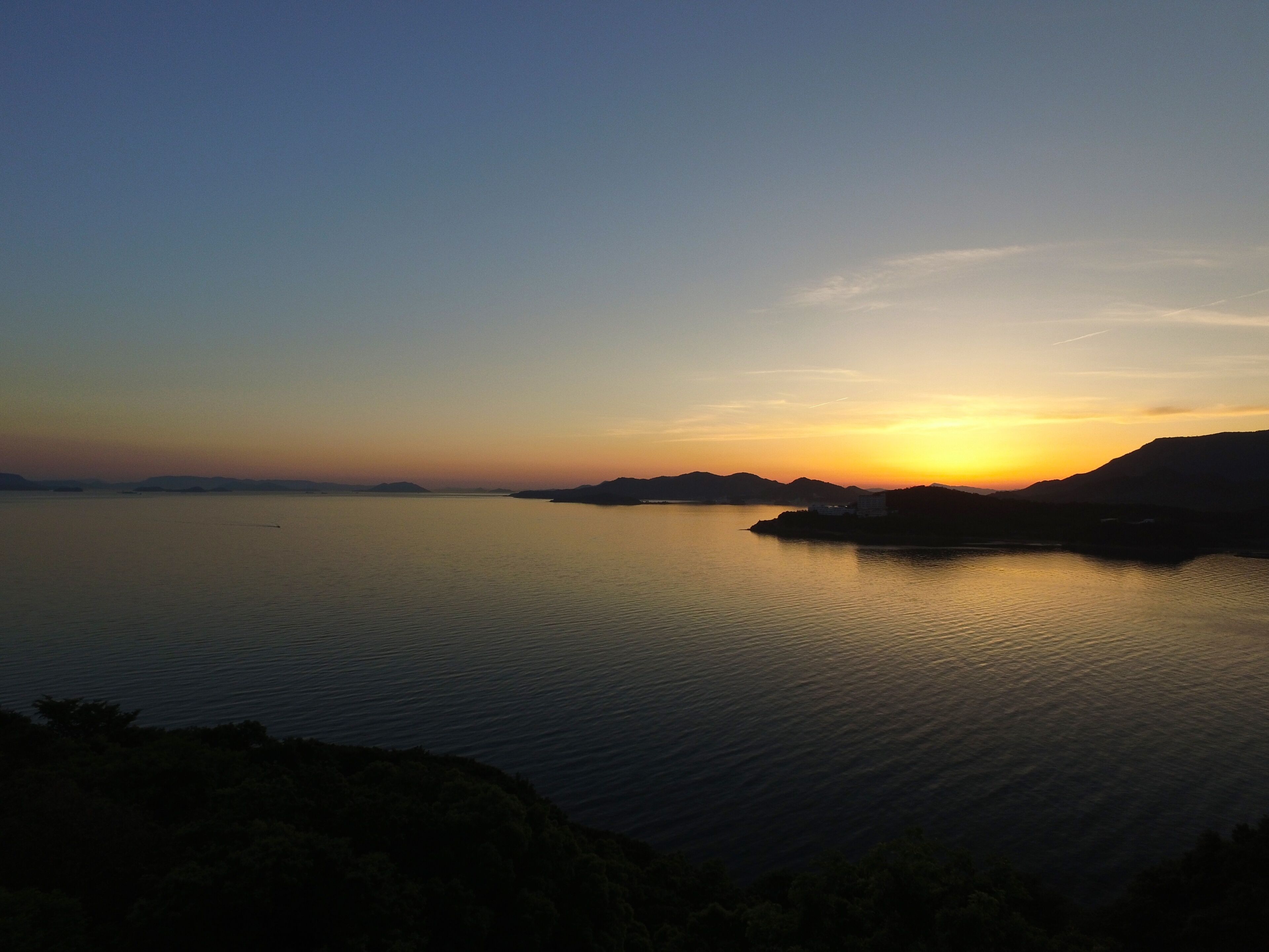 A calm body of water with distant landforms and a clear sky.