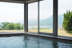 A pool area with large windows offering a view of a lake and mountains. - Kokumin Shukusya Shodoshima (Shodoshima)