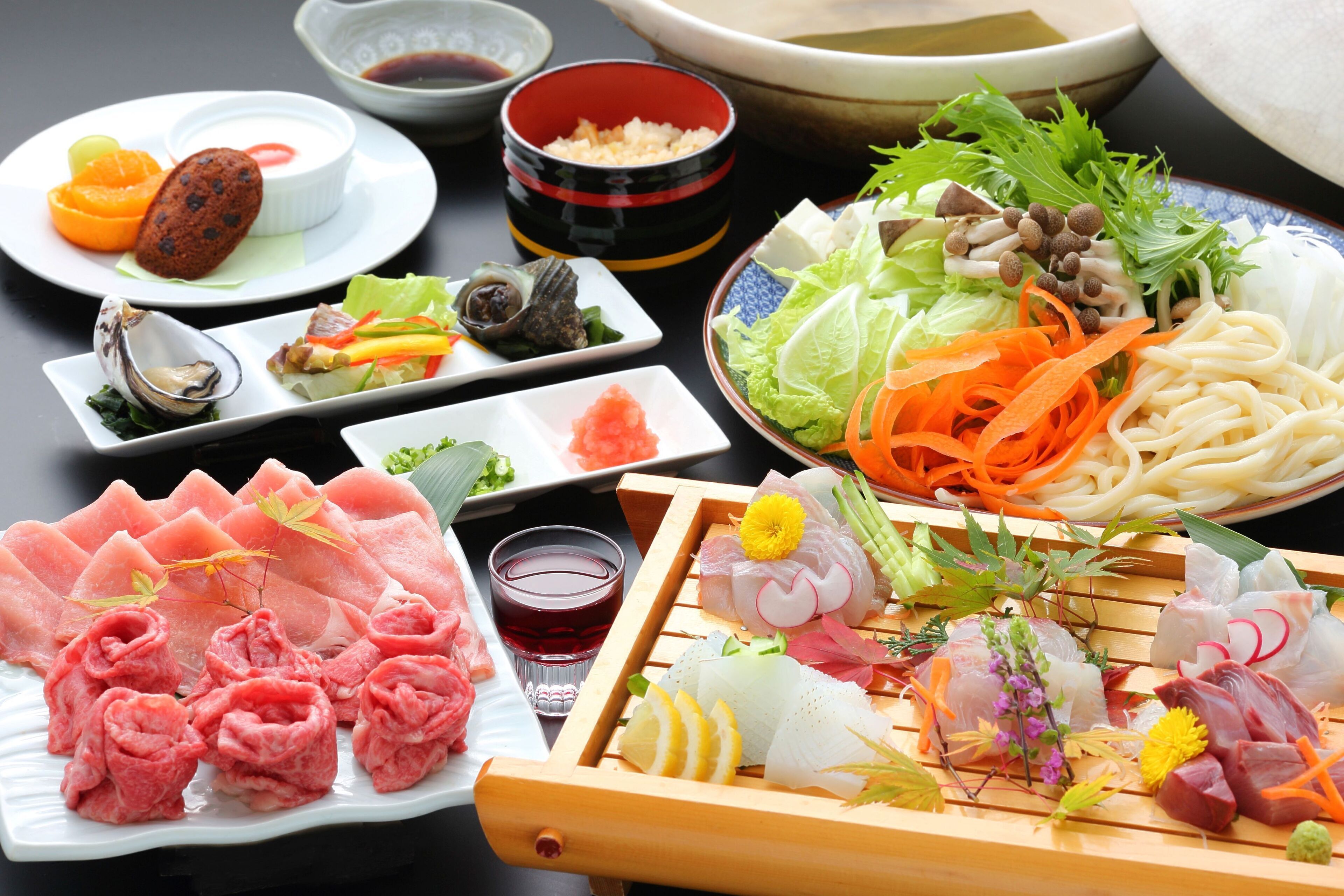 A variety of Japanese dishes including sashimi, vegetables, and noodles.