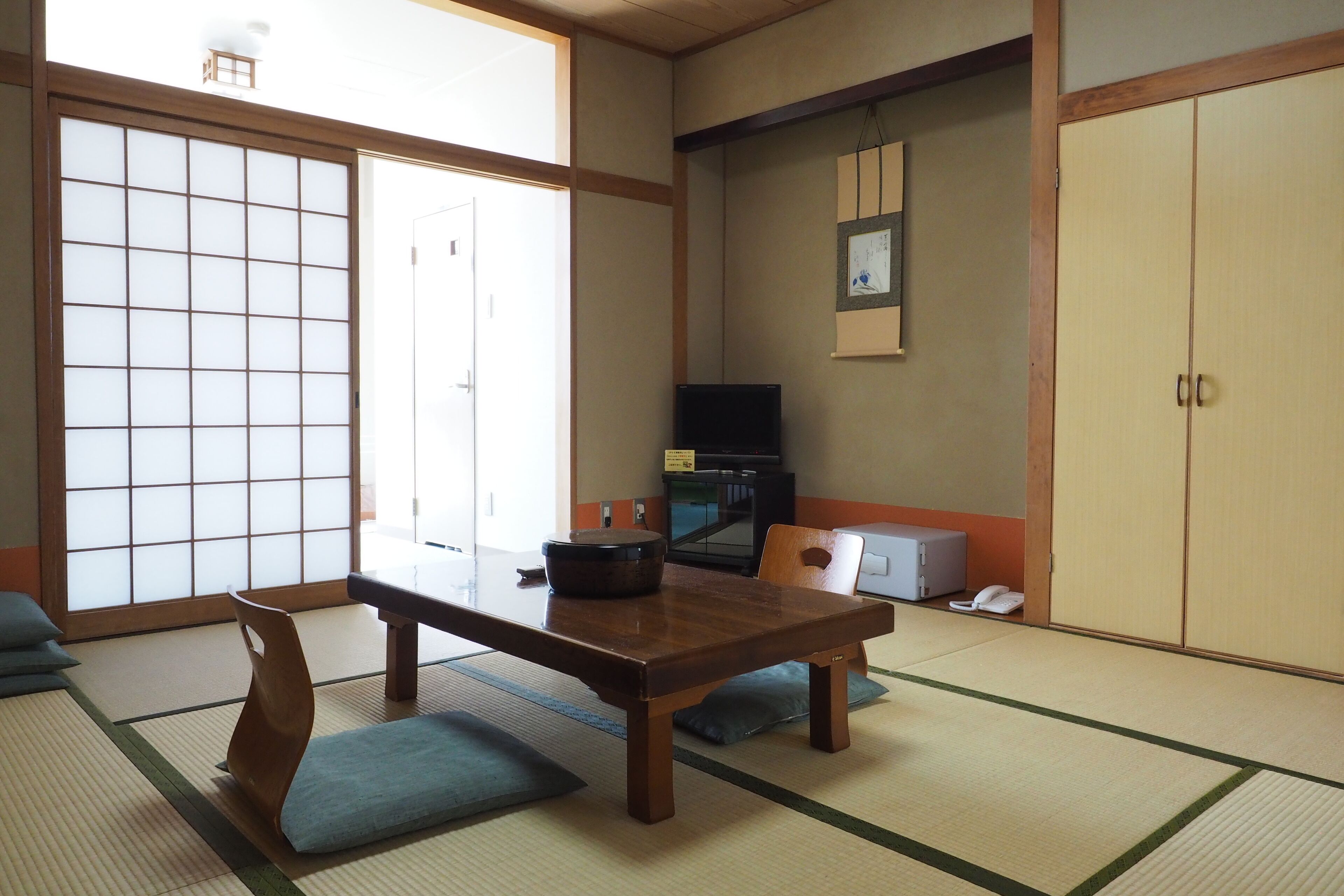 Een traditionele Japanse kamer met tatami vloeren, een lage tafel, een televisie en schuifdeuren.