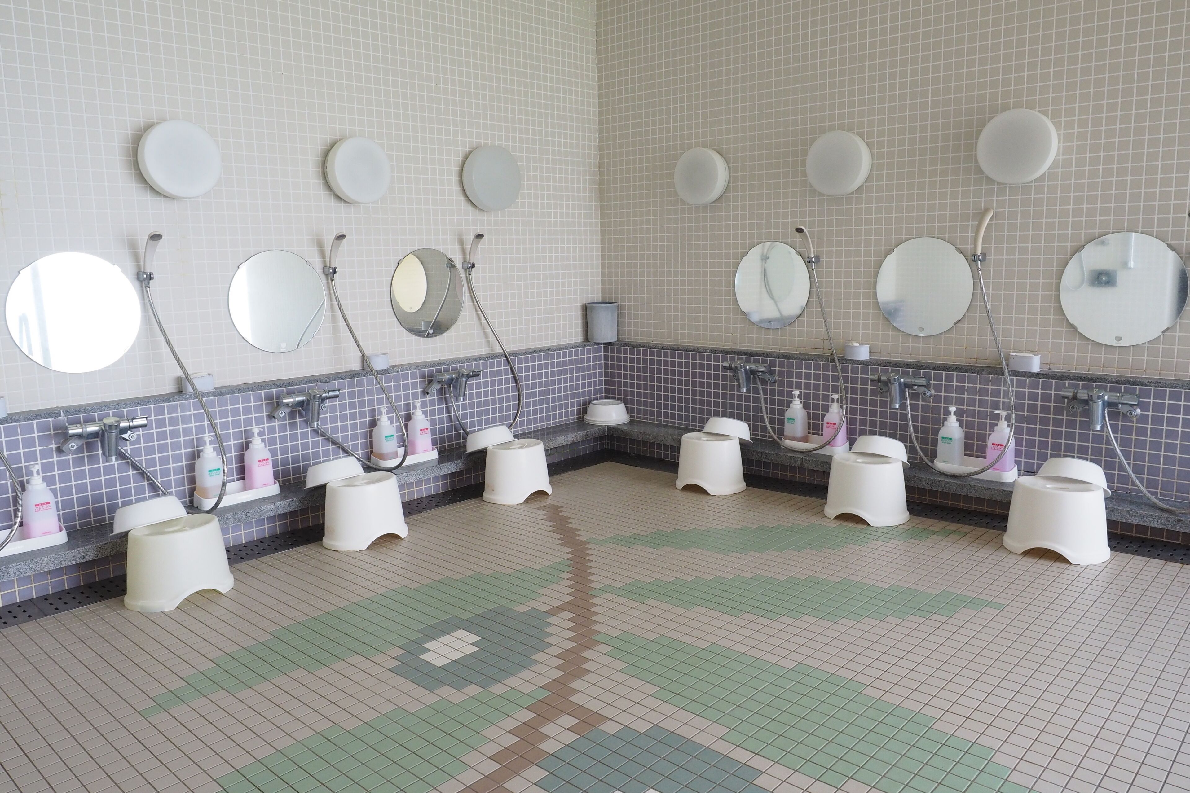 A public restroom with multiple sinks, mirrors, and toilet paper dispensers.
