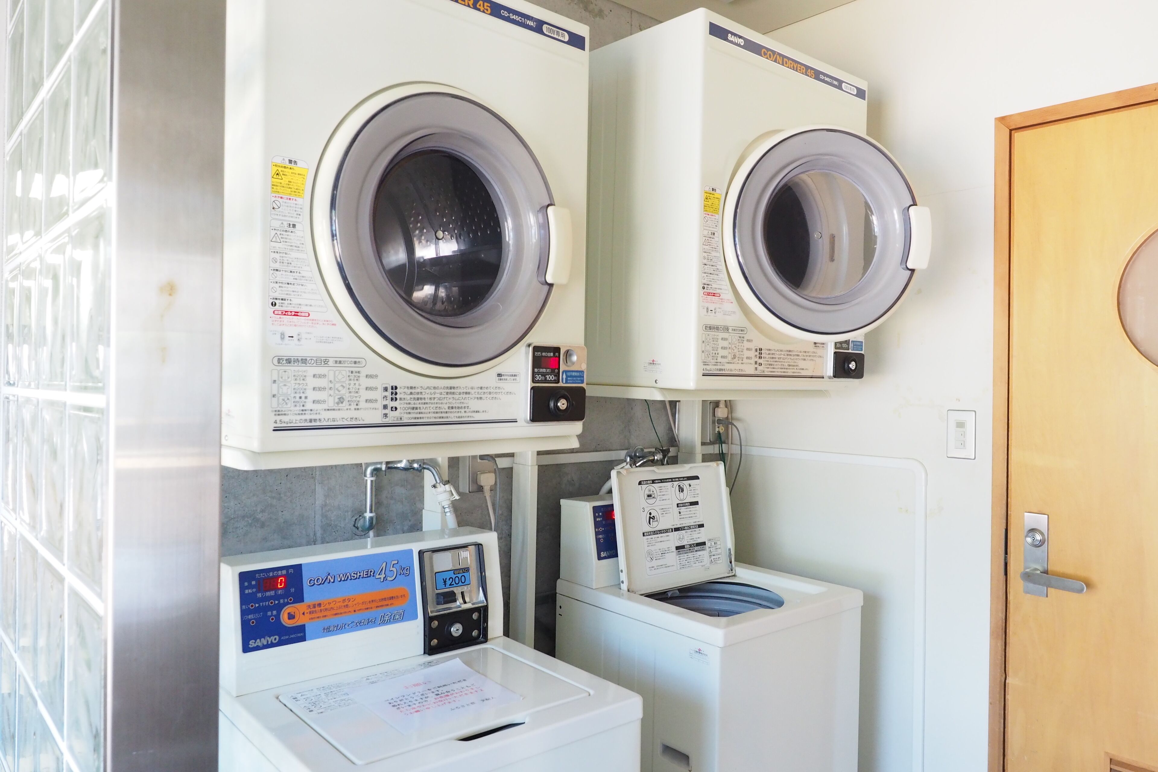 A laundry area with two front-loading washing machines and a coin-operated dryer.