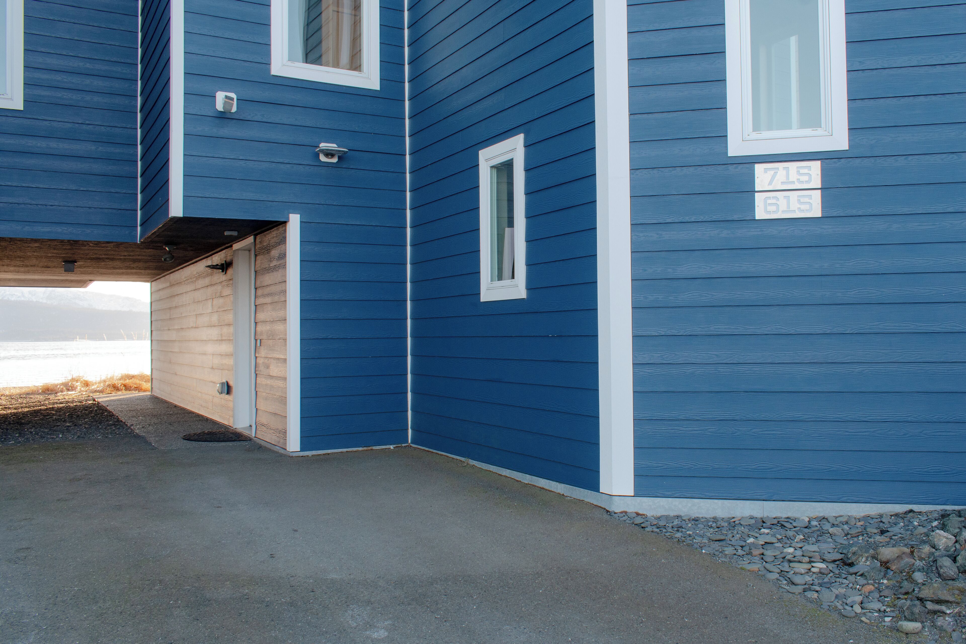 Une maison bleue avec une porte de garage, une petite fenêtre et une boîte aux lettres.
