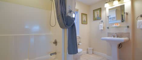 A bathroom with a bathtub, toilet, sink, and shower curtain.