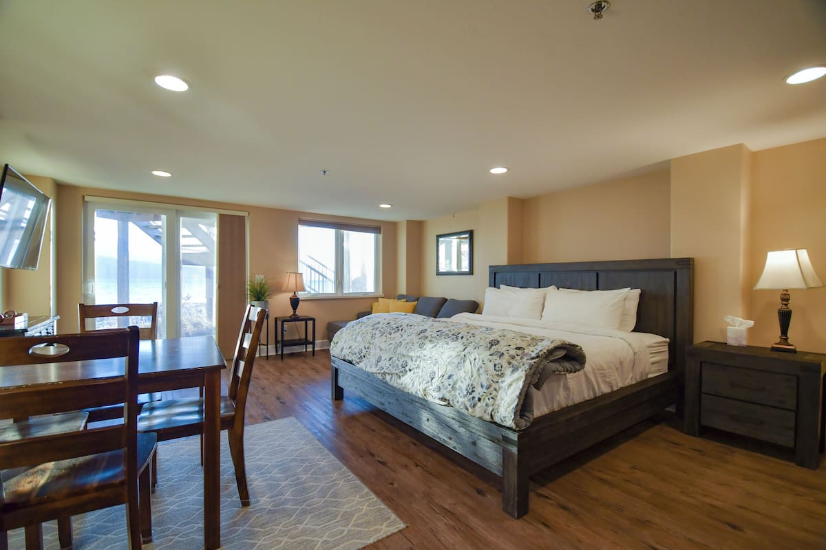 A bedroom with a large bed, a desk, and chairs.