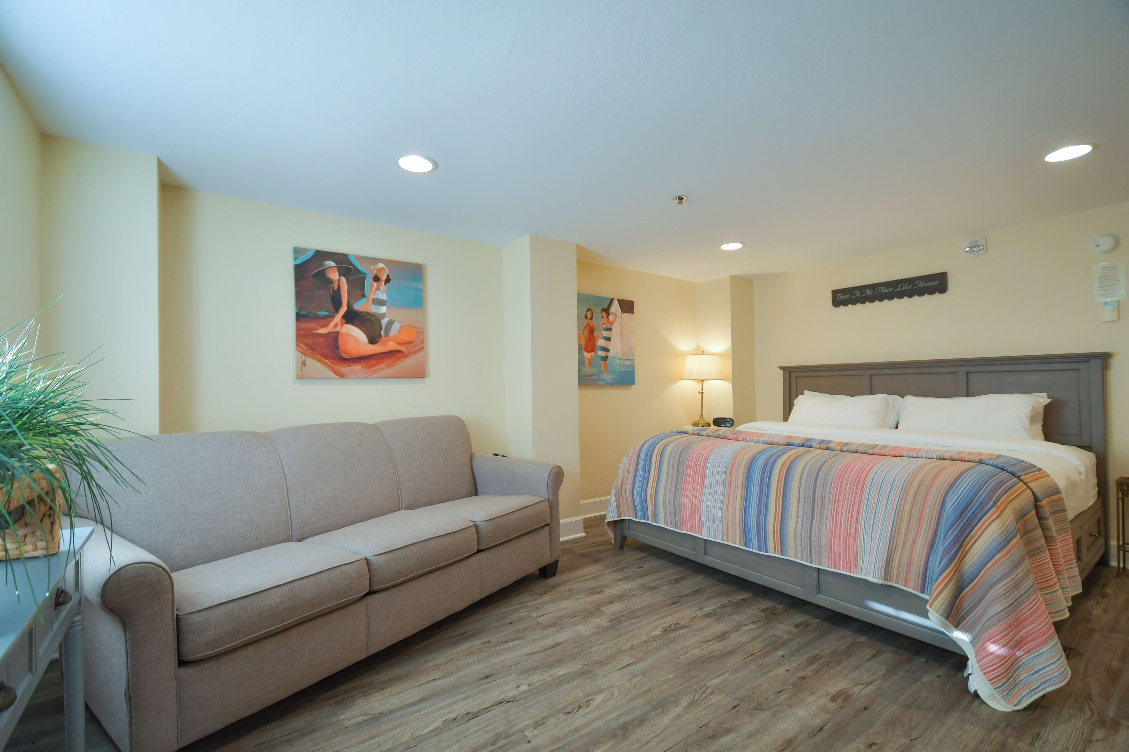 A bedroom with a bed, a sofa, and a painting on the wall.