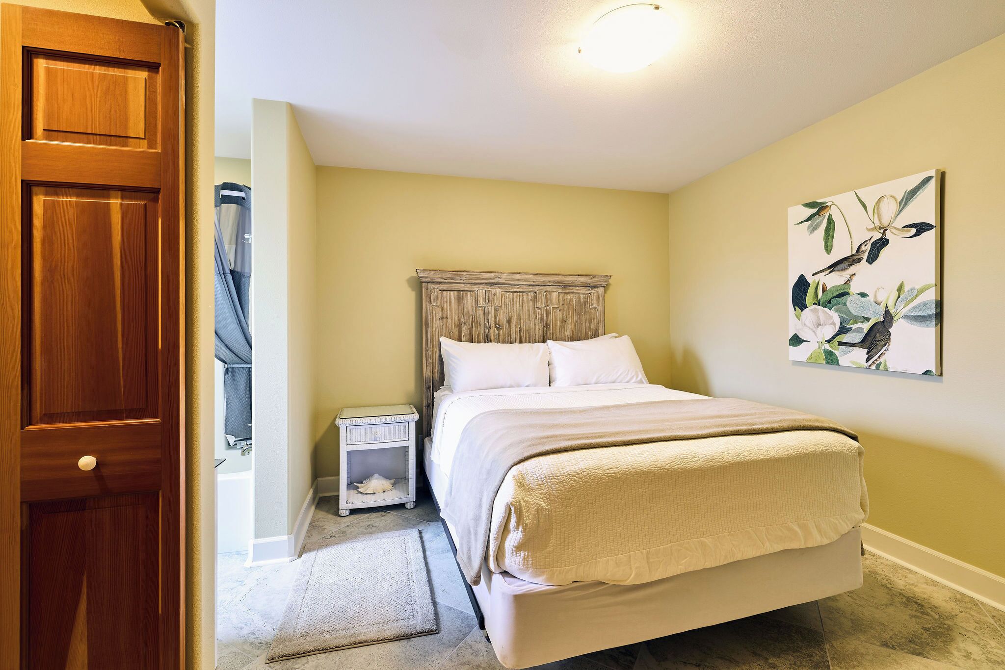 A bedroom with a bed, nightstand, and a door.