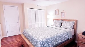 A bedroom with a bed, a wardrobe, a bedside table, and a nightstand.