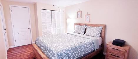 Un dormitorio con cama, armario, mesita de noche y mesilla.