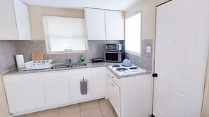 A compact kitchen with white cabinets, a microwave, a toaster, and a gas stove.