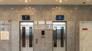 A modern elevator with a digital display, flanked by marble walls and a floor with a light wood finish. - Toyoko Inn Kobe Sannomiya Ekimae (Kobe)