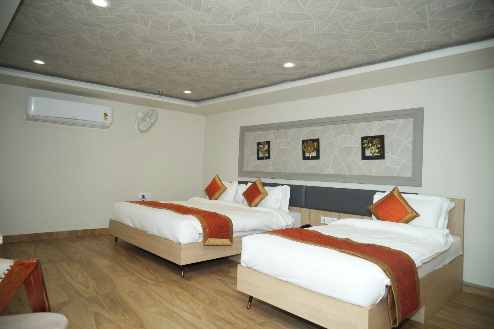 Ein Hotelzimmer mit zwei Betten, einem Deckenventilator, einer Klimaanlage und einer Wanduhr.