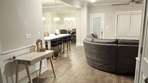 Een moderne keuken met een gebogen grijs aanrecht, houten vloer en witte kasten.