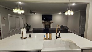 Een moderne keuken met een groot eiland, inbouwapparatuur en een flatscreen televisie boven de open haard.