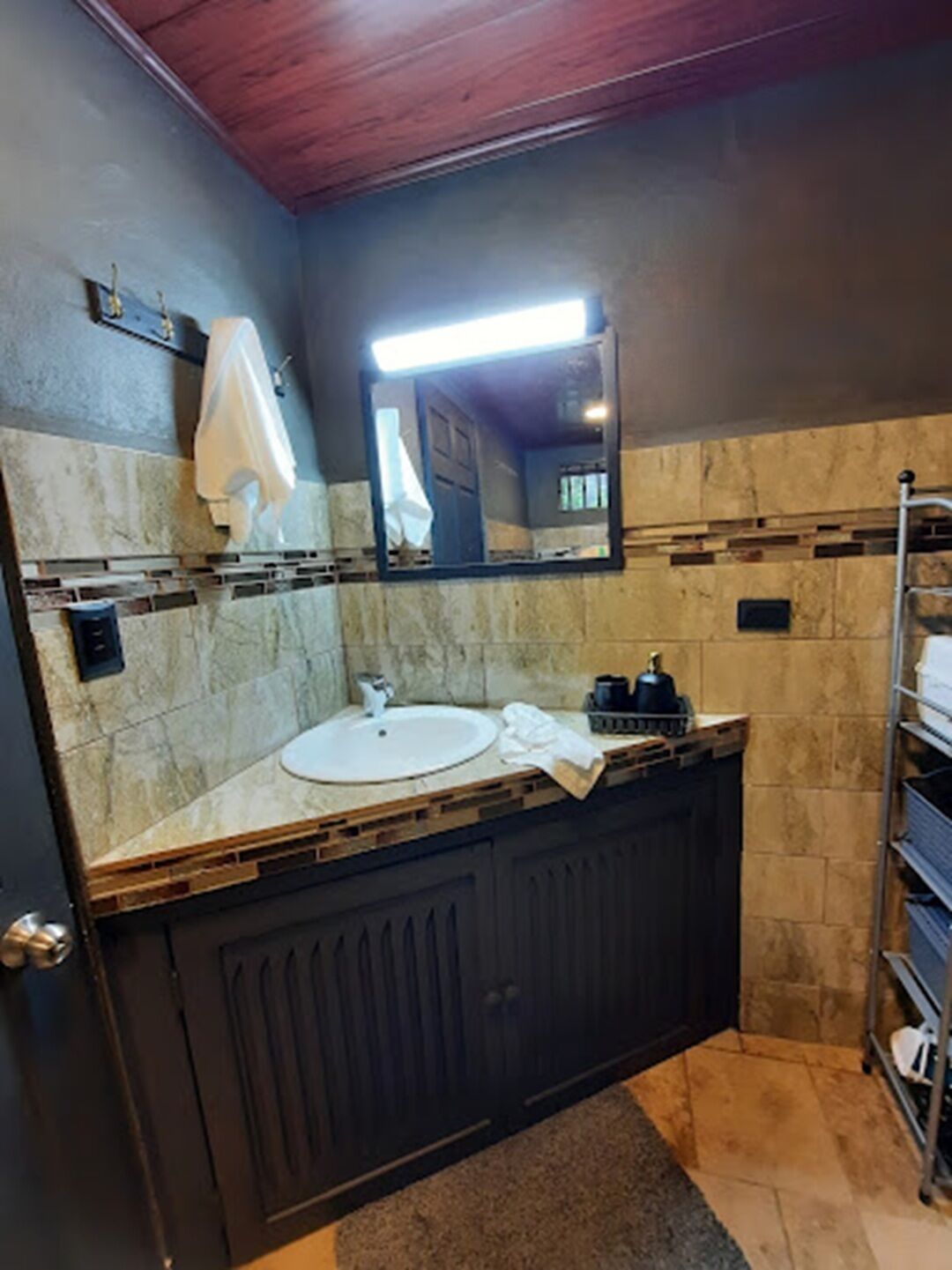 A bathroom with a sink, mirror, towel rack, and a towel hanging on the wall.