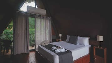 Un dormitorio con una cama grande, dos mesitas de noche con lámparas, una ventana con cortinas y vistas al exterior.