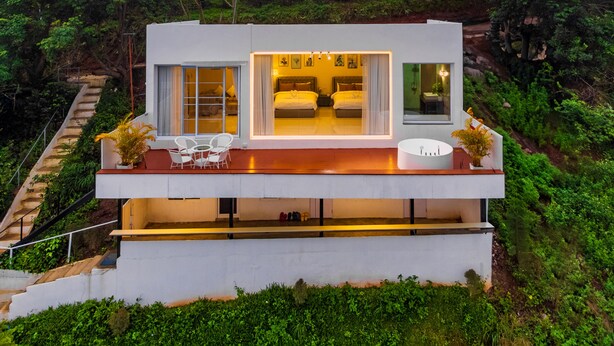 Ein modernes, zweistöckiges Haus mit Balkon, Essbereich und Schlafzimmer mit zwei Betten.