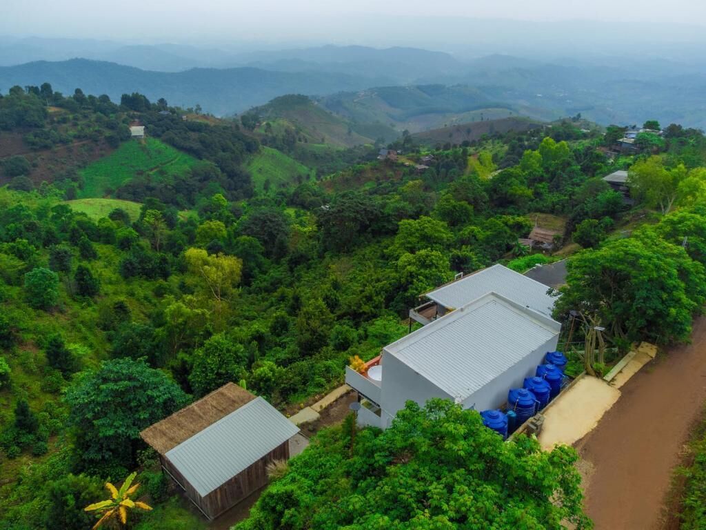 A rural landscape with a white building, a dirt path, and a view of distant hills.