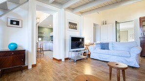 Un salón moderno con un sofá blanco, una mesa de centro de madera y un televisor sobre un mueble.