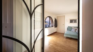 Una sala de estar moderna con piso de madera, un sofá azul claro y vista a través de un ventanal arqueado.