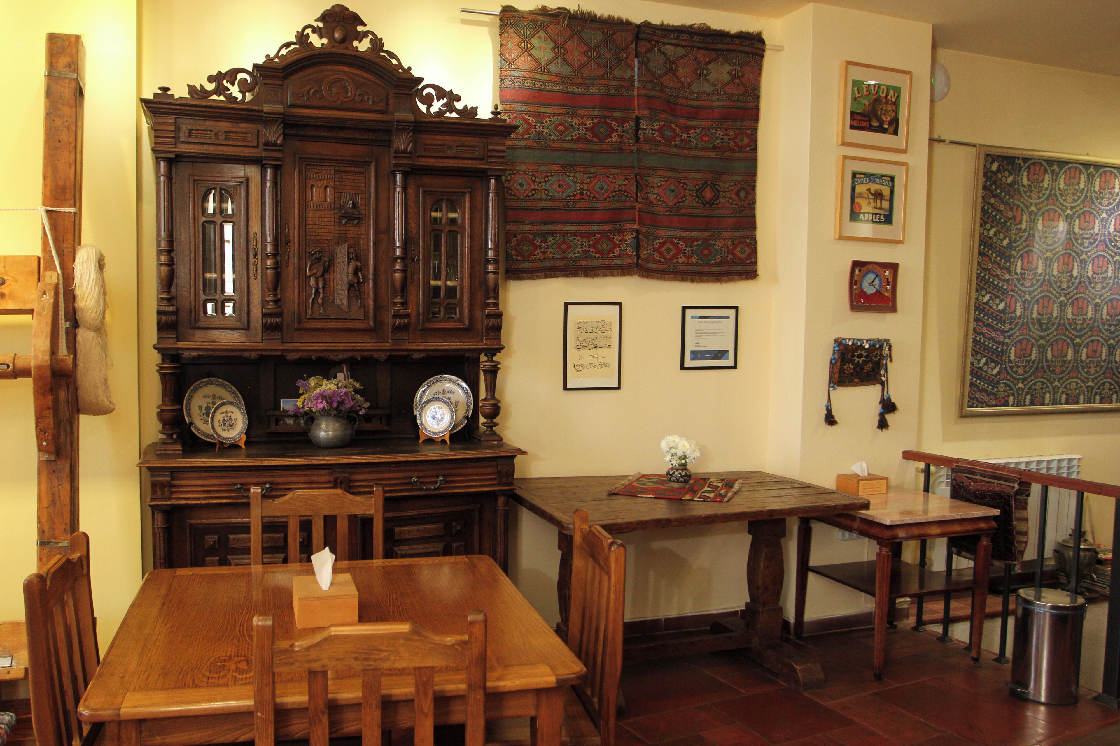 A traditional dining room with a wooden table and chairs, a large wooden cabinet, and a patterned tapestry on the wall.