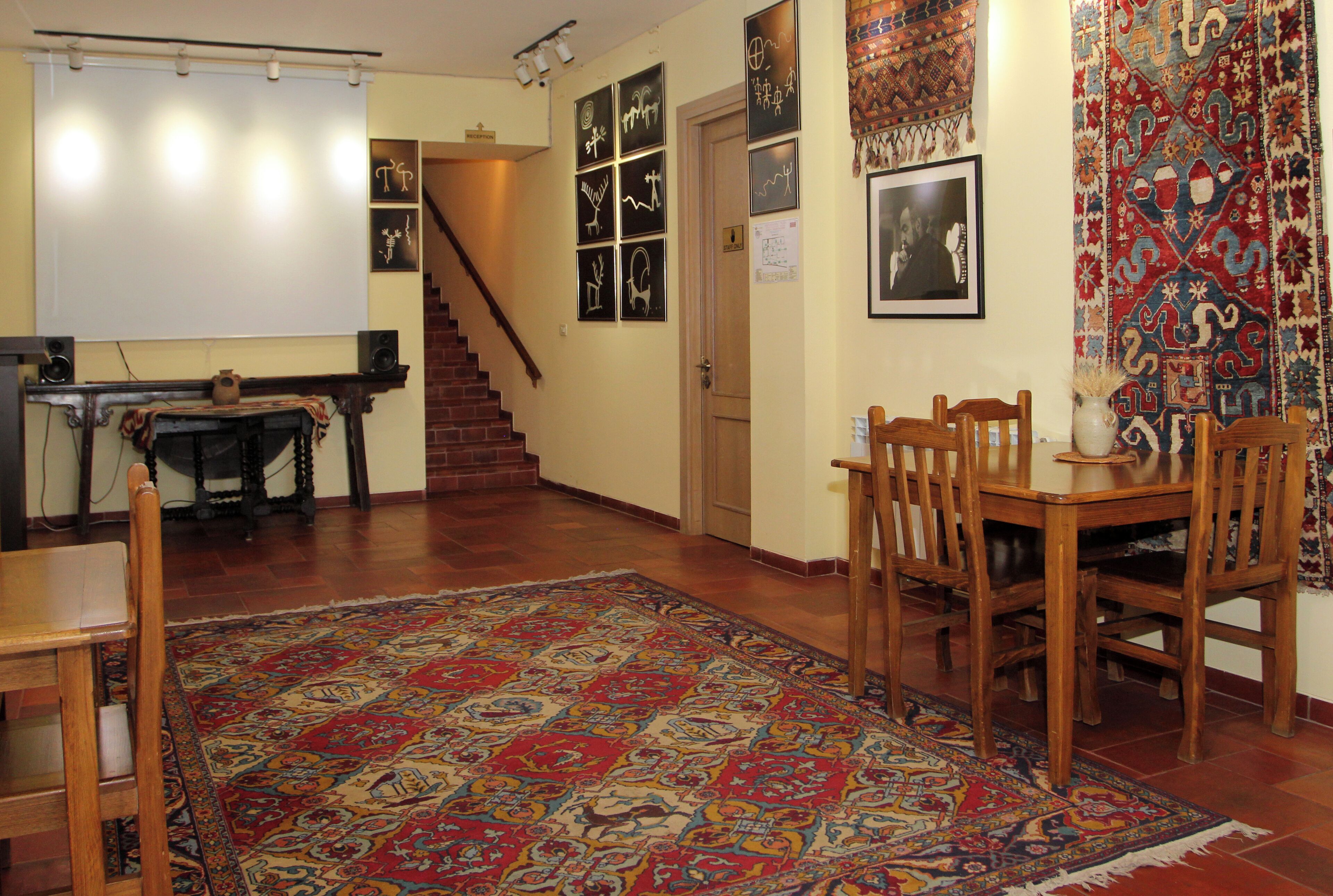 A spacious living room with a large rug, wooden furniture, a fireplace, and a staircase leading to another level.