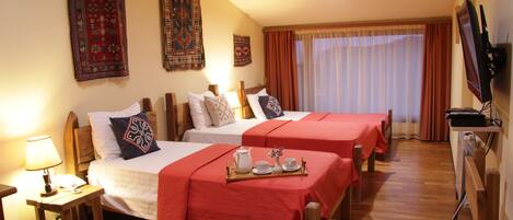 A hotel room with two beds, a TV, and a tray with tea and cups.