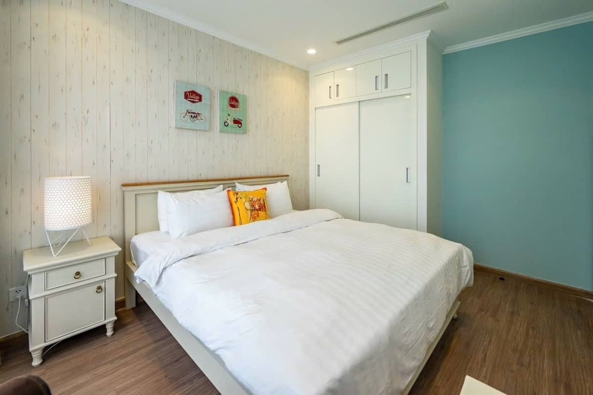 A bedroom with a bed, a nightstand, a lamp, a wardrobe, and wall decorations.