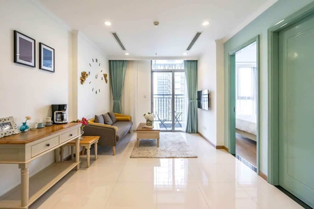 A modern living room with a sofa, coffee table, and a dining area.