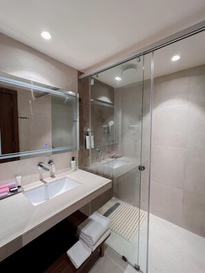 A modern bathroom with a glass-enclosed shower, a large mirror, and a vanity with a sink and toiletries. - Tulip Inn Bhopal (Bhopal)