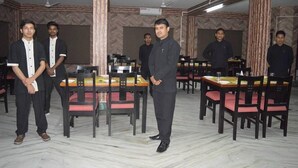 A dining area with multiple tables and chairs, a ceiling fan, and a patterned wall. - Hotel Yumi Ragi (Papumpare)