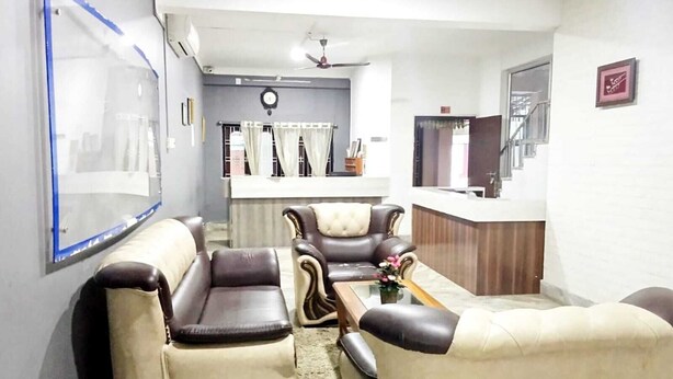 A living room with two leather sofas, a coffee table, and a reception desk. - Hotel Yumi Ragi (Papumpare)