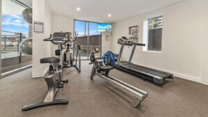 A gym with cardio machines, weight equipment, and a large window with a city view. - Stylish 1-Bed Studio in Vibrant South Brisbane (South Brisbane)