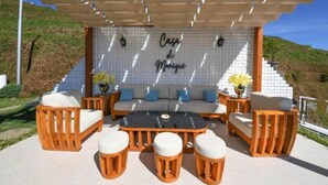 Un espacio exterior con asientos, un sofá, sillas de madera y una mesa.