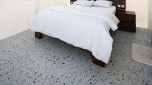 Un dormitorio con cama, cabecera de madera, mesita de noche, ventilador de techo y ventana con vistas a zonas verdes.