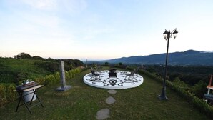 Un espacio al aire libre con mesa y sillas circulares, una parrilla y un farol.