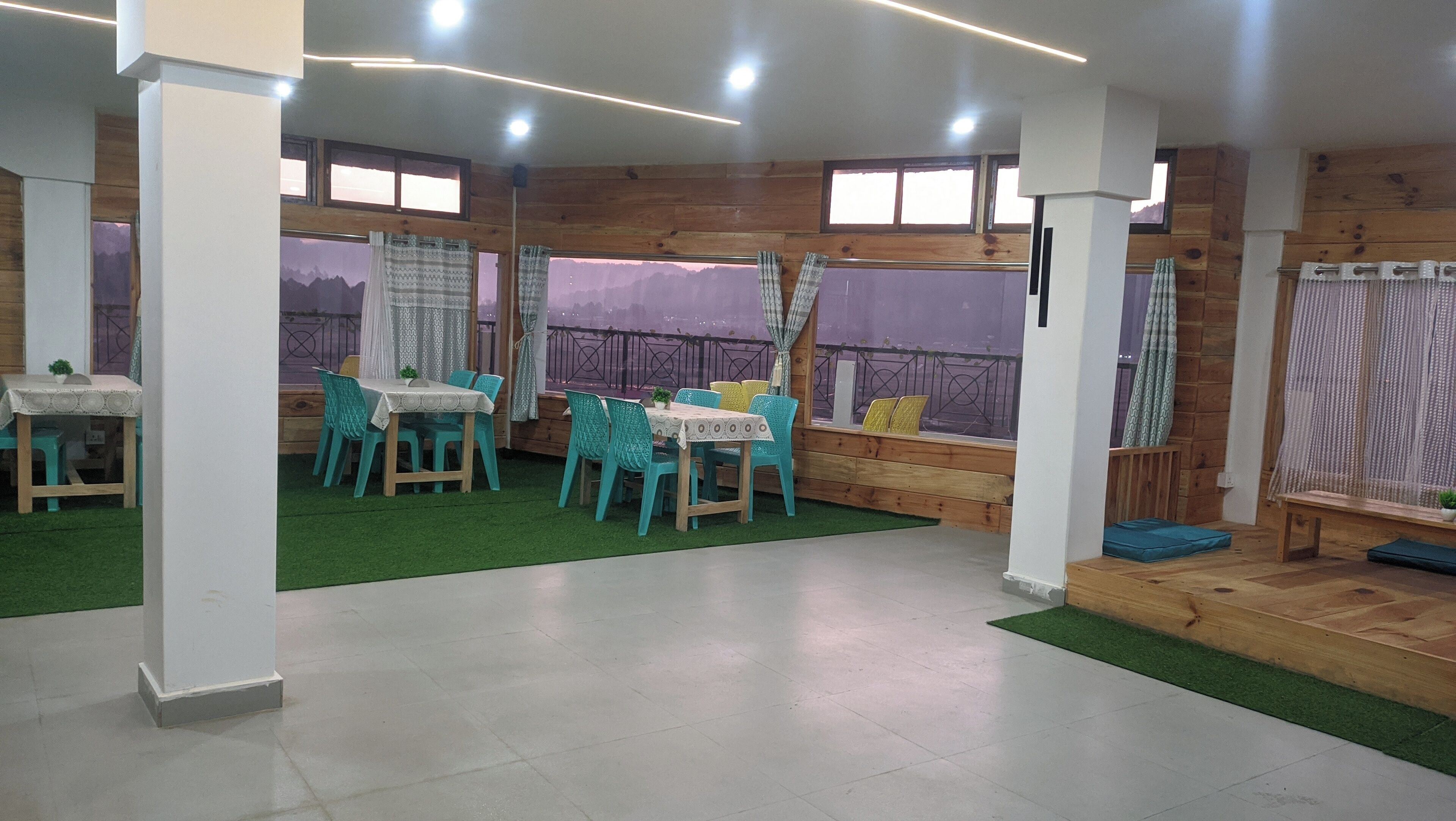 Un espace de restauration intérieur accueillant, avec des murs en bois, un gazon artificiel vert et une table entourée de chaises.