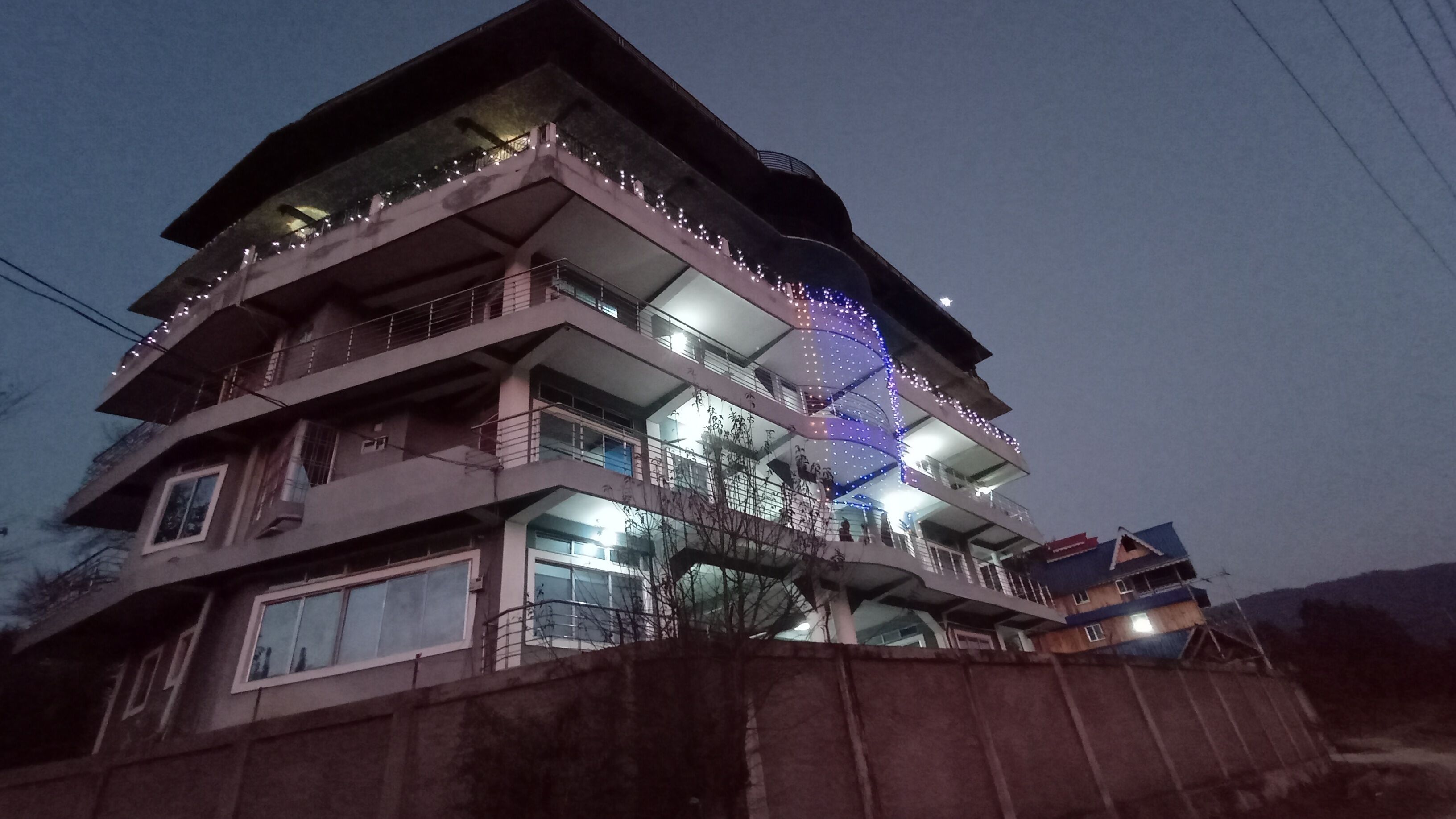 A multi-story building with balconies and string lights.