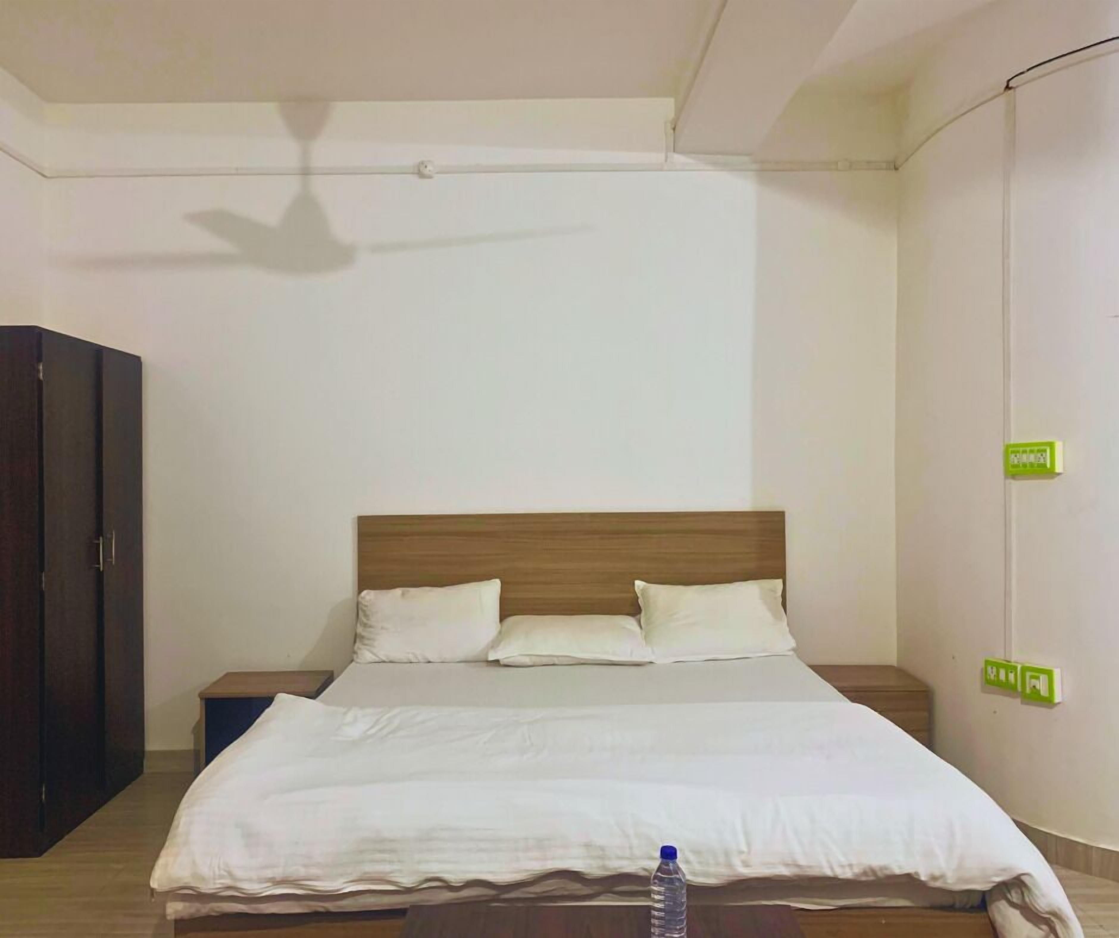 A neatly made bed with a wooden headboard, a nightstand, and a wardrobe.
