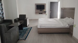 Camera d'albergo moderna con un letto, un divano, una TV a parete e pavimento in legno.