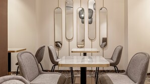 A dining area with a marble table and four grey upholstered chairs. - Le Madame by Sweett (Paris)