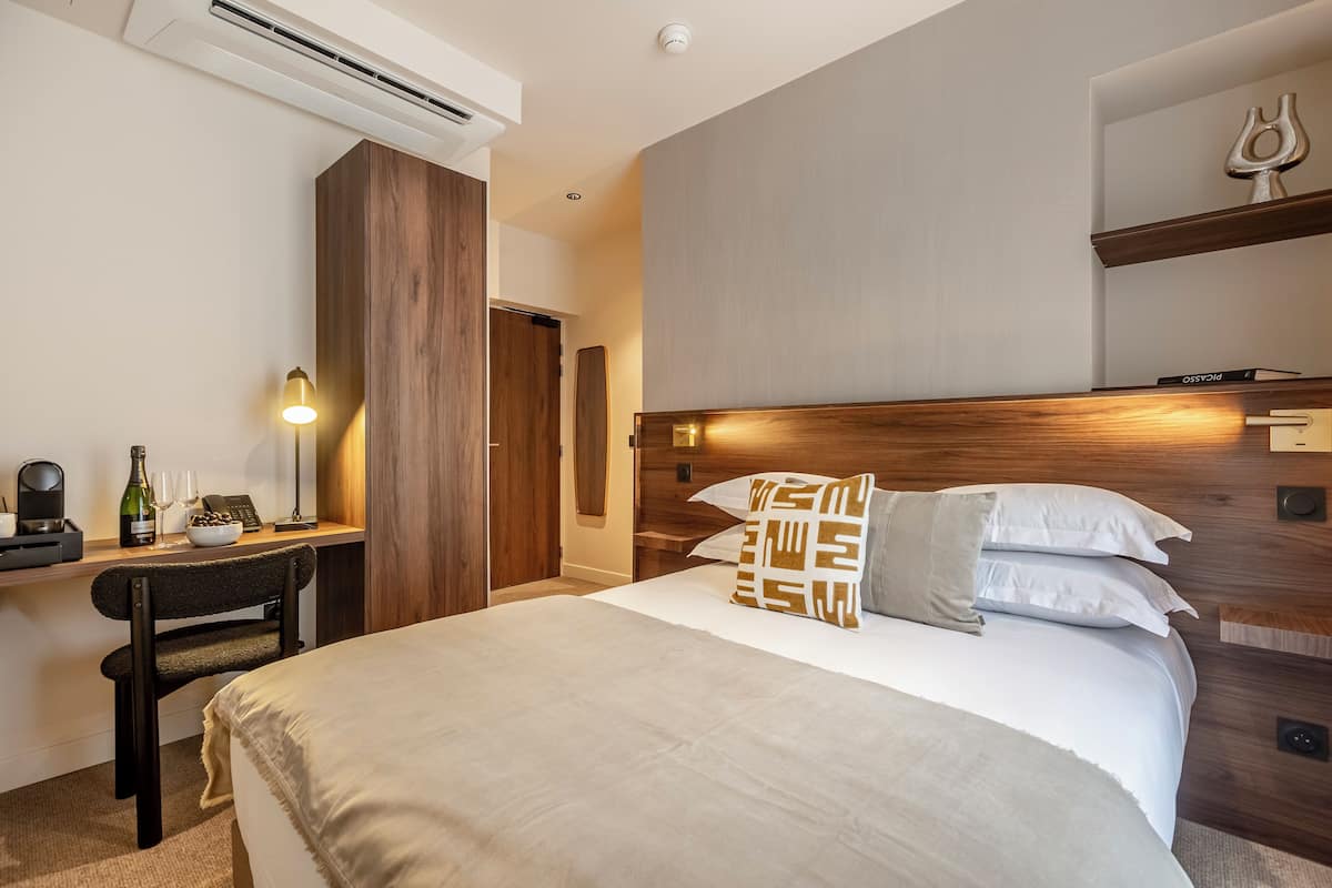Ein Hotelzimmer mit Bett, Nachttisch, Schreibtisch, Stuhl und einer kleinen Ablage mit Dekoration.