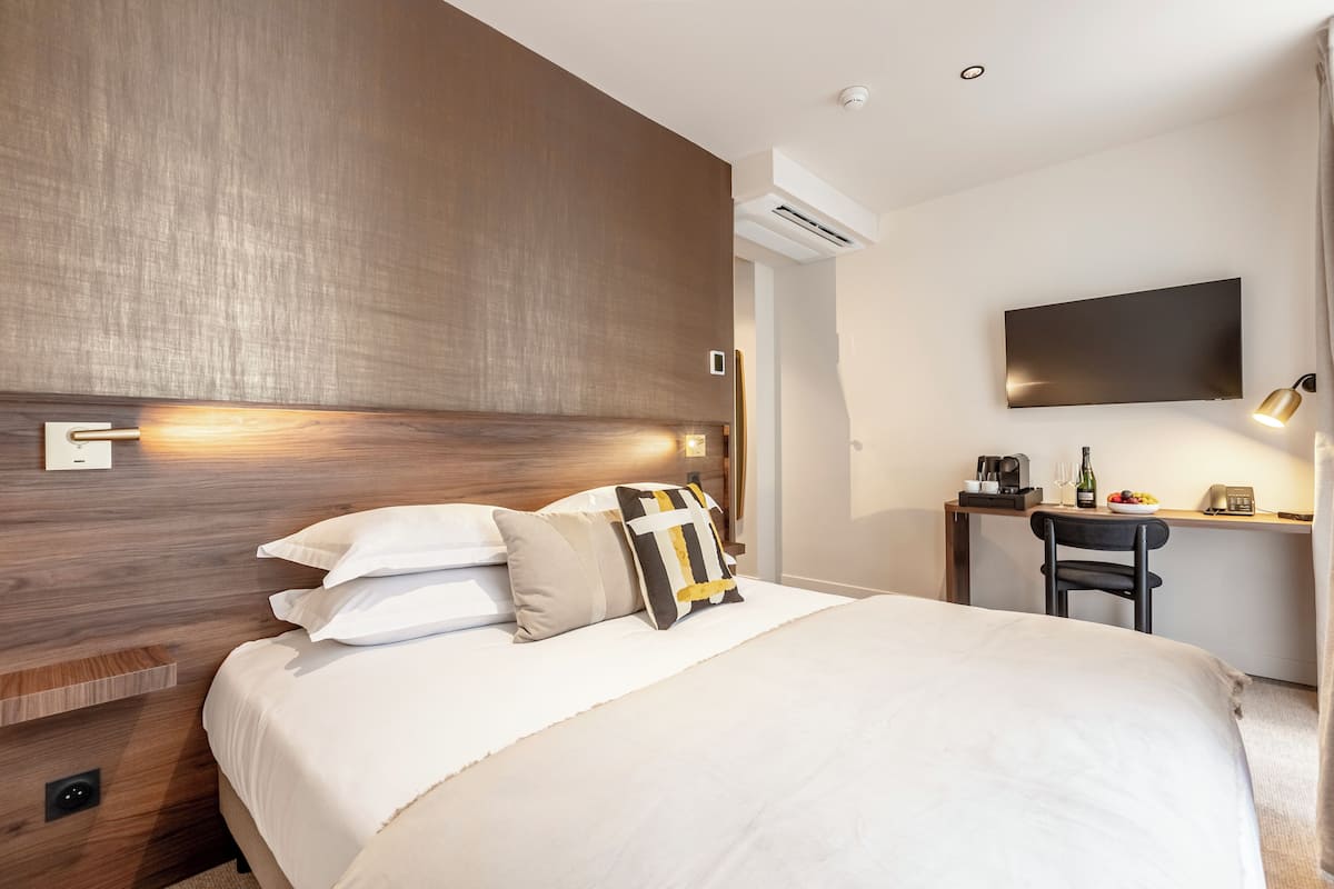Ein modernes Hotelzimmer mit einem großen Bett, einem Schreibtisch, einem Flachbildfernseher und einer Kaffeemaschine.
