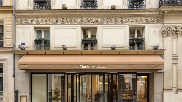 A building with a classic architectural style, featuring ornate balconies and a large awning with the name "Le Madame by Sweettt". - Le Madame by Sweett (Paris)