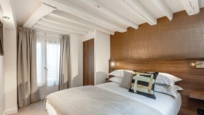 A bedroom with a large bed, wooden headboard, and a window with curtains. - Le Madame by Sweett (Paris)