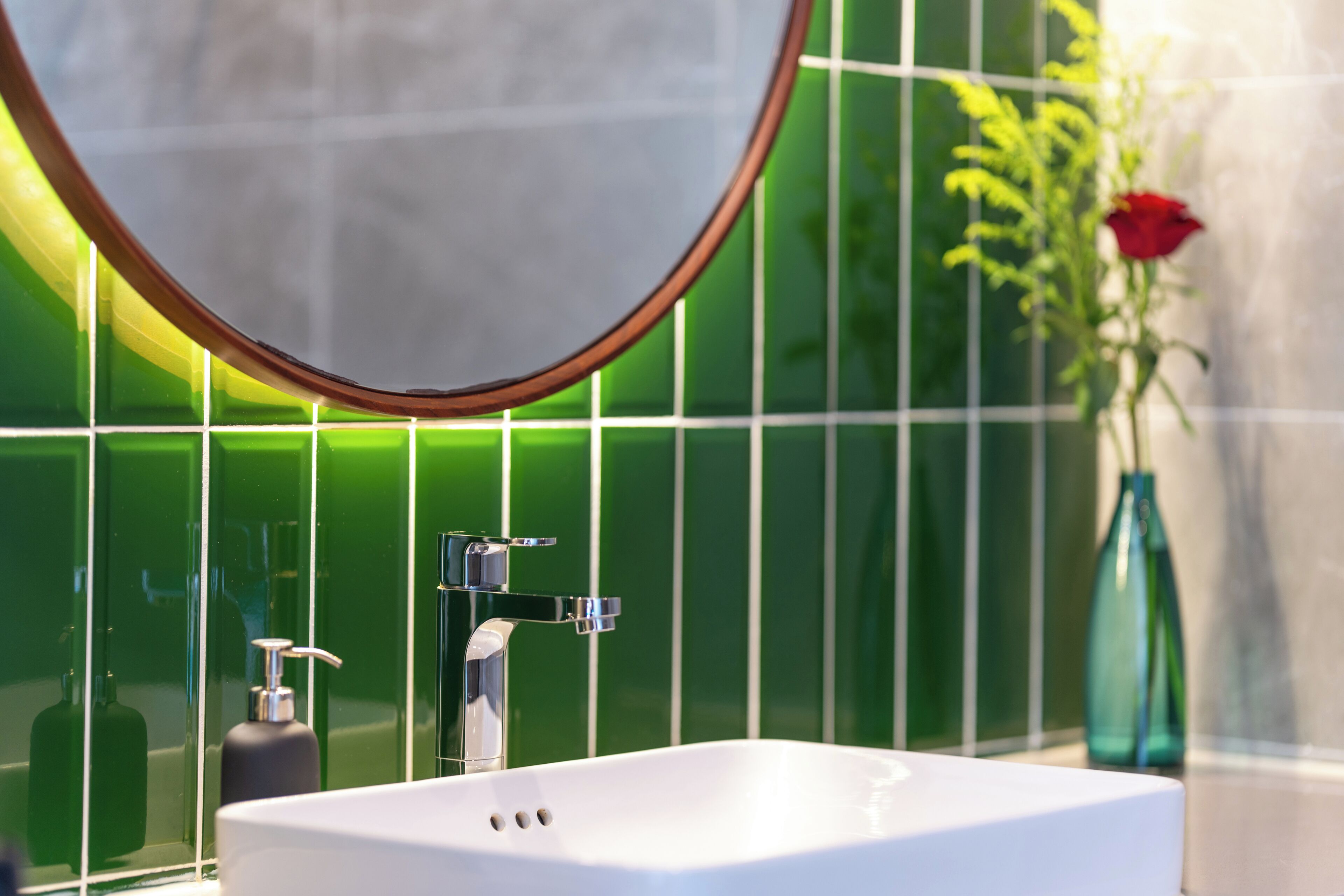 A bathroom with a white sink, chrome faucet, and a mirror above it.